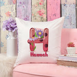 Decorative pillow with a floral letter 'H' and name 'Hannah' on a pink couch with a floral wall background.