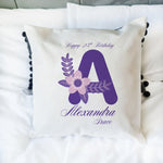 Decorative pillow with a purple letter 'A' and floral design, featuring text on a white background.