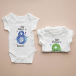 Two baby onesies with milestone prints on a beige background