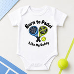 White “Born to padel like my Daddy” baby bodysuit with blue and green crossed rackets and a yellow ball.