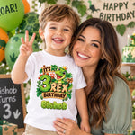 Woman with a smiling child wearing a personalised Bishop “3 Rex birthday” T-shirt at a dinosaur-themed celebration.