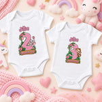 Two white personalised safari milestone bodysuits showing pink number 2 and green number 3 animal designs.