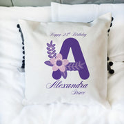 Decorative pillow with a purple letter 'A' and floral design, featuring text on a white background.