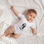 Baby wearing a white onesie with text and graphics on a white blanket