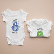 Two baby onesies with milestone prints on a beige background