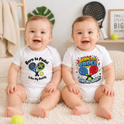 Two smiling babies wearing white “Born to padel like my Daddy” bodysuits in different racket-themed designs.