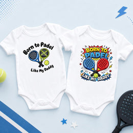 Two white padel baby bodysuits showing crossed racket artwork and a colourful “Born to padel like my Daddy” design.