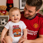 Man in a Manchester United shirt holding a smiling baby in a personalised Edison football supporter bodysuit.