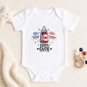 A white short-sleeve baby bodysuit laid flat on a cream fabric background, featuring a graphic print of a baby bottle with the Union Jack and Canadian flag, surrounded by the text '50% British', '50% Canadian', and '100% CUTE'. A soft star toy, knitted blanket, and wooden bead rattle are placed around it.