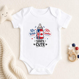 A white short-sleeve baby bodysuit laid flat on a cream fabric background, featuring a graphic print of a baby bottle with the Union Jack and Canadian flag, surrounded by the text '50% British', '50% Canadian', and '100% CUTE'. A soft star toy, knitted blanket, and wooden bead rattle are placed around it.