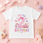 White second birthday T-shirt with a pink number 2, unicorn, princess carriage and butterflies on a pink background.
