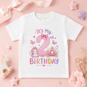 White second birthday T-shirt with a pink number 2, unicorn, princess carriage and butterflies on a pink background.