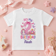 White personalised Aleah second birthday T-shirt with a pink number 2, unicorn, princess carriage and butterflies.