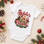 White personalised first Christmas 2026 baby bodysuit with a teddy bear, gifts and red and green decorations.
