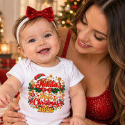 Woman holding a smiling baby wearing a personalised first Christmas 2026 bodysuit with red and green decorations.