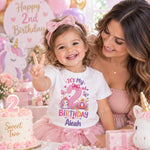 Woman with a smiling child wearing a personalised Aleah second birthday T-shirt and pink tutu at a birthday celebration.