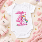 White personalised 4 months old baby bodysuit with a pink number and rainbow-maned unicorn on pink.