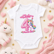White personalised 4 months old baby bodysuit with a pink number and rainbow-maned unicorn on pink.