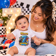 Woman with a smiling baby wearing a personalised 7 months old racing bodysuit beside balloons and a lit number 7.