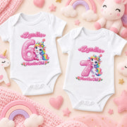 Two white personalised unicorn milestone bodysuits with pink numbers 6 and 7 and pastel nursery props.