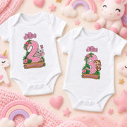 Two white personalised safari milestone bodysuits showing pink number 2 and green number 3 animal designs.