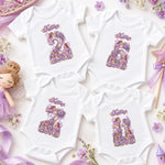 Four white personalised fairy princess milestone bodysuits with ornate purple floral numbers, crowns and pastel props.