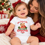 Woman holding a smiling baby wearing a personalised first Christmas teddy bear bodysuit and red bow.